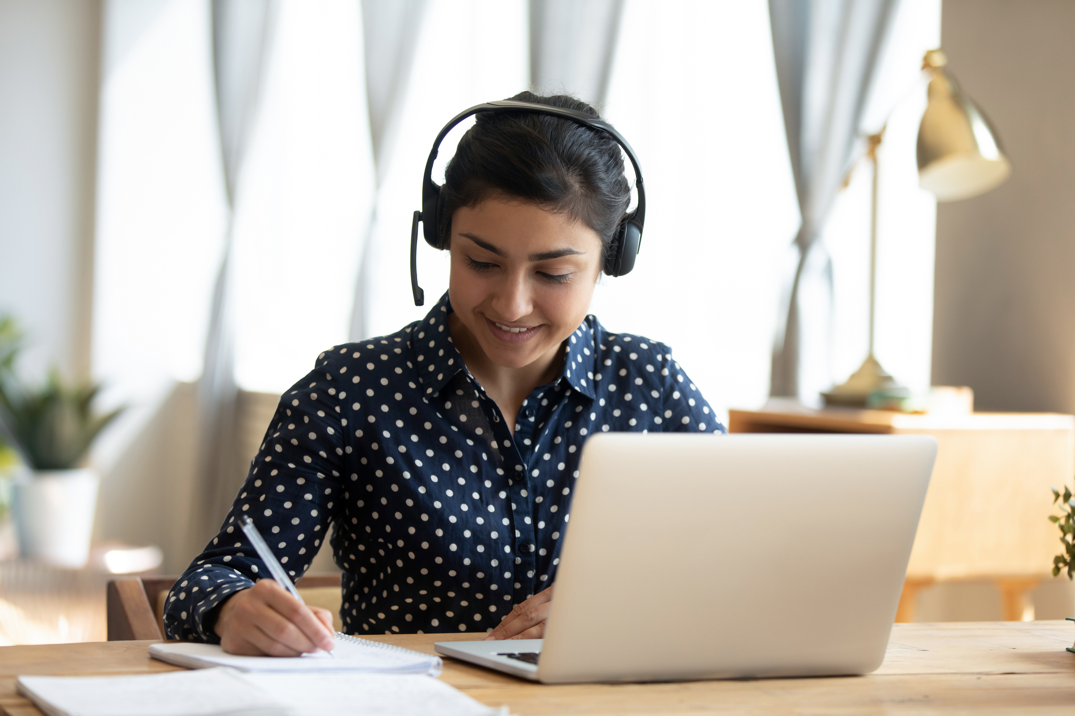 Online learning student listening to classes while taking notes